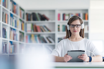 Image showing female student study in library, using tablet and searching for 