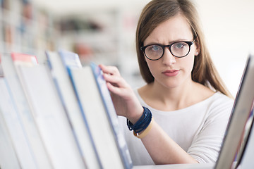 Image showing portrait of famale student selecting book to read in library