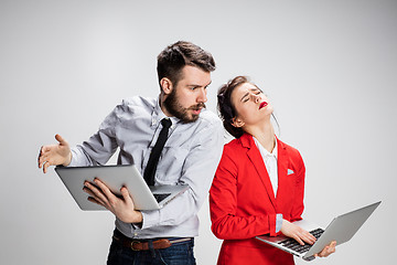 Image showing The young businessman and businesswoman with laptops on gray background