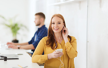 Image showing woman with earphones and smartphone at office