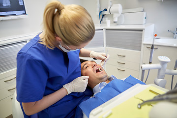 Image showing female dentist checking up male patient teeth