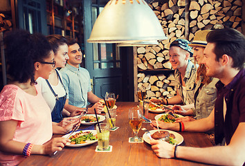 Image showing happy friends eating and drinking at bar or pub