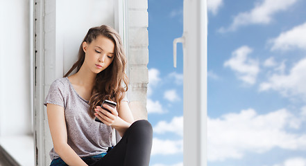 Image showing sad pretty teenage girl with smartphone texting