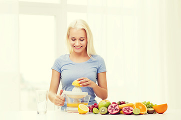 Image showing smiling woman squeezing fruit juice at home