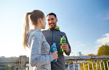 Image showing smiling couple with bottles of water outdoors