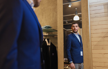 Image showing man trying jacket on at mirror in clothing store