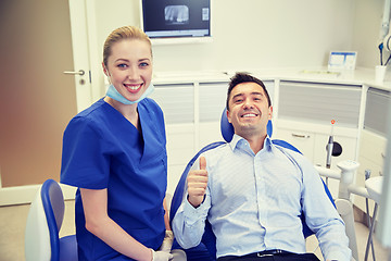 Image showing happy female dentist with man patient at clinic