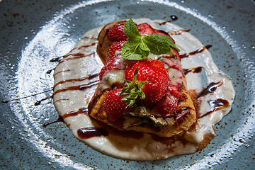 Image showing Whole wheat Belgium waffle topped with syrup, whipped cream, walnuts and freshly chopped strawberries 