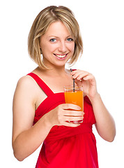 Image showing Young woman is drinking carrot juice