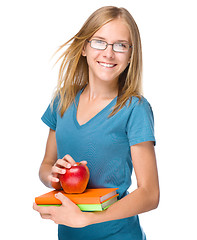 Image showing Young student girl is holding book and apple