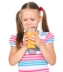 Image showing Little girl unwillingly drinking orange juice