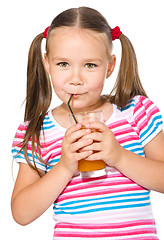 Image showing Little girl is drinking carrot juice