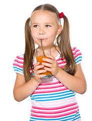 Image showing Little girl is drinking carrot juice