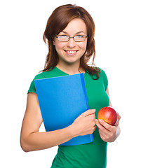 Image showing Young student girl is holding book and apple