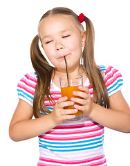 Image showing Little girl is drinking carrot juice