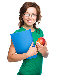 Image showing Young student girl is holding book and apple