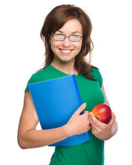 Image showing Young student girl is holding book and apple