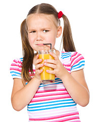 Image showing Little girl unwillingly drinking orange juice