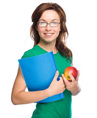 Image showing Young student girl is holding book and apple