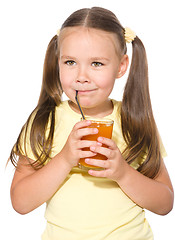 Image showing Little girl is drinking carrot juice