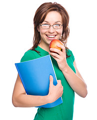 Image showing Young student girl is holding book and apple