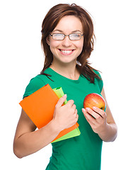 Image showing Young student girl is holding book and apple