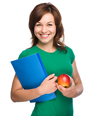 Image showing Young student girl is holding book and apple