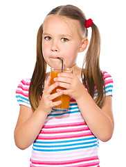 Image showing Little girl is drinking carrot juice