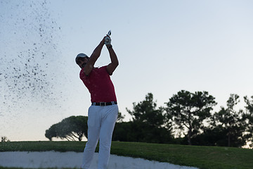 Image showing golfer hitting a sand bunker shot on sunset