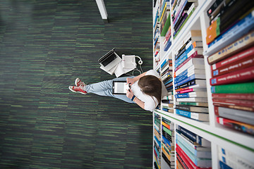 Image showing female student study in library, using tablet and searching for 