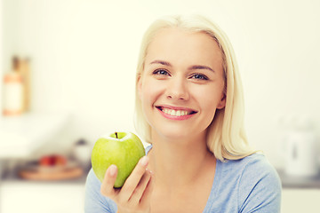 Image showing happy woman eating green apple on kitchen