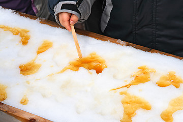 Image showing Child putting on a sick maple taffy