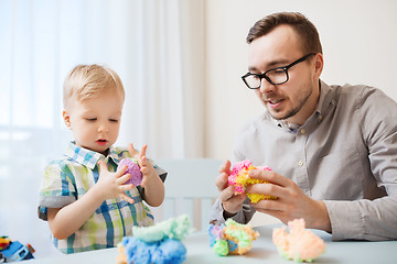 Image showing father and son playing with ball clay at home