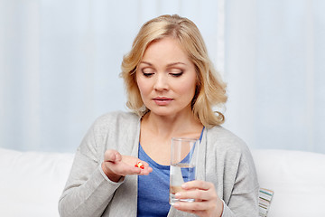 Image showing woman with medicine and water glass at home