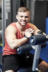 Image showing smiling man sitting on exercise bench in gym