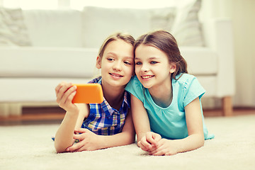 Image showing happy girls with smartphone taking selfie at home