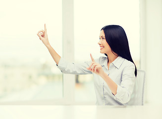 Image showing smiling woman pointing to something imaginary