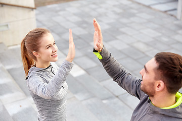 Image showing smiling couple making high five on city street