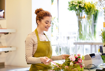 Image showing smiling florist woman making bunch at flower shop