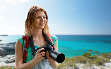Image showing happy woman with backpack and camera over seashore