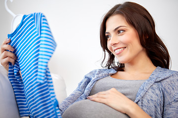 Image showing happy woman holding baby boys bodysuit at home