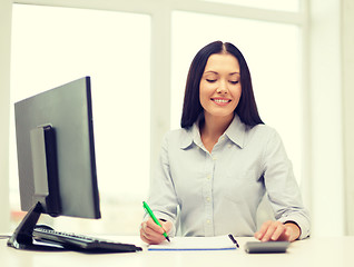 Image showing woman with computer, notebook and calculator