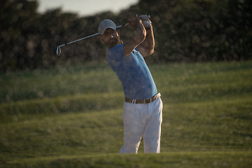 Image showing golfer hitting a sand bunker shot on sunset