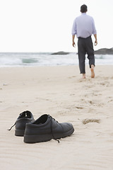 Image showing Businessman walking barefoot on beach