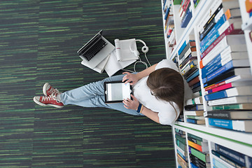 Image showing female student study in library, using tablet and searching for 