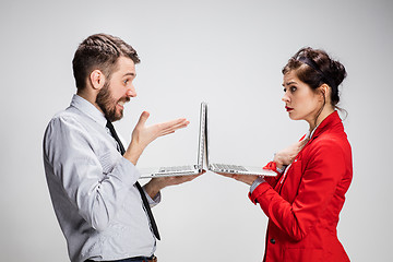 Image showing The young businessman and businesswoman with laptops on gray background