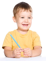 Image showing Little boy is drawing using color pencils