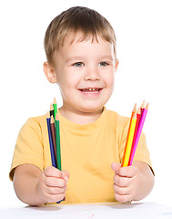 Image showing Little boy is drawing using color pencils