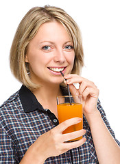 Image showing Young woman is drinking carrot juice