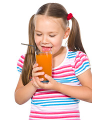 Image showing Little girl is drinking carrot juice